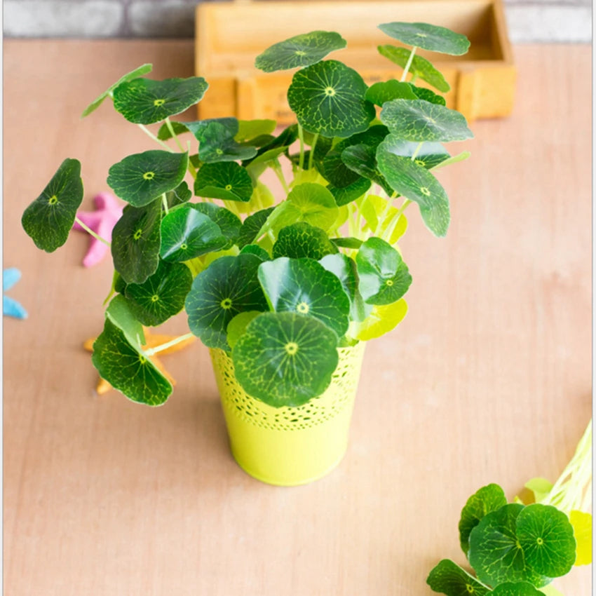 Artificial potted plant with round, deep green lotus-style leaves in a bright yellow decorative metal planter.