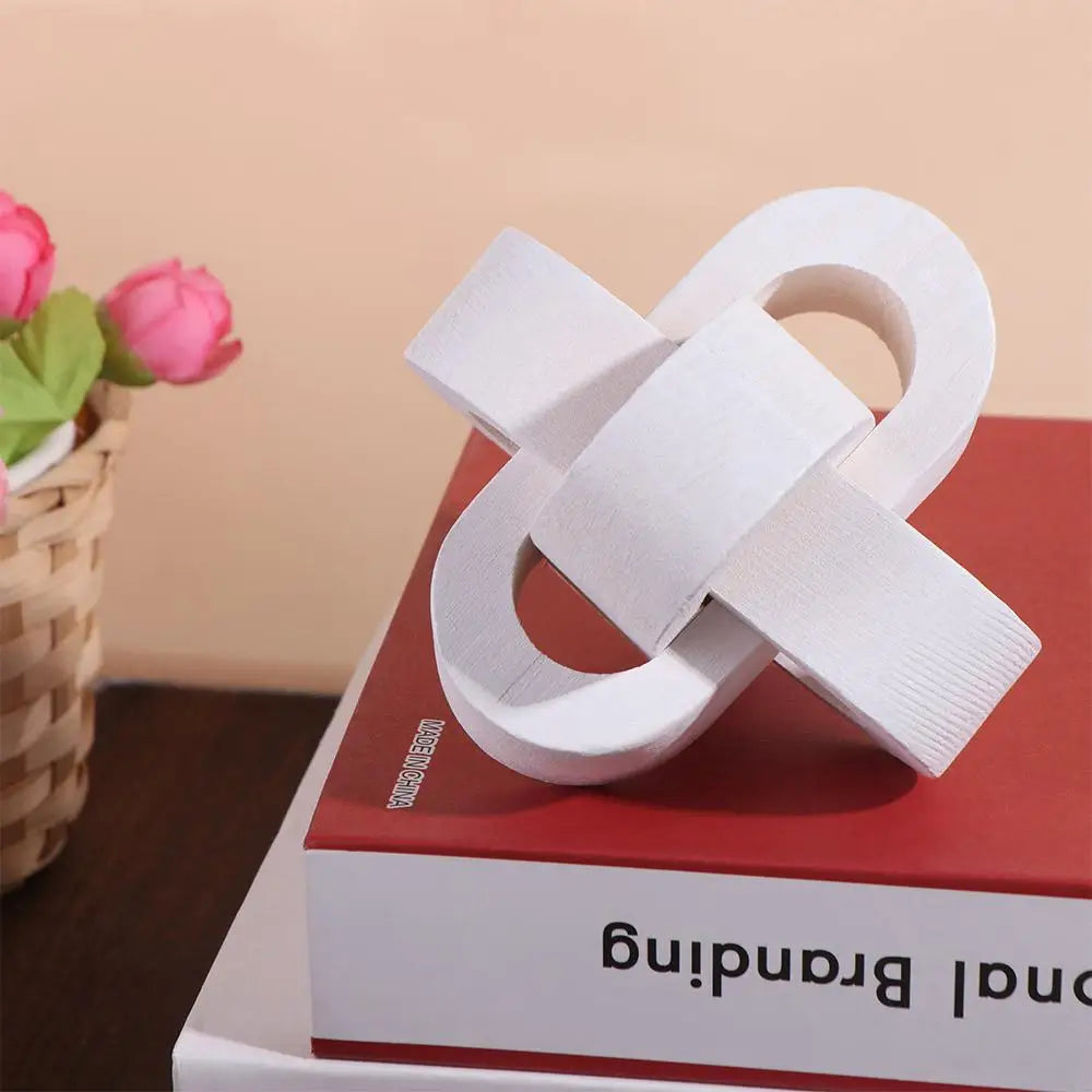 Modern white wooden decorative knot sculpture on a red book, styled for contemporary home decor.