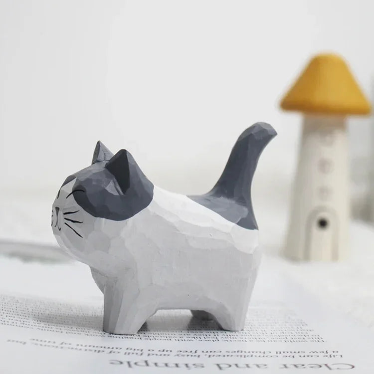 Small carved wooden cat figurine with a grey and white painted finish and a unique geometric faceted texture.