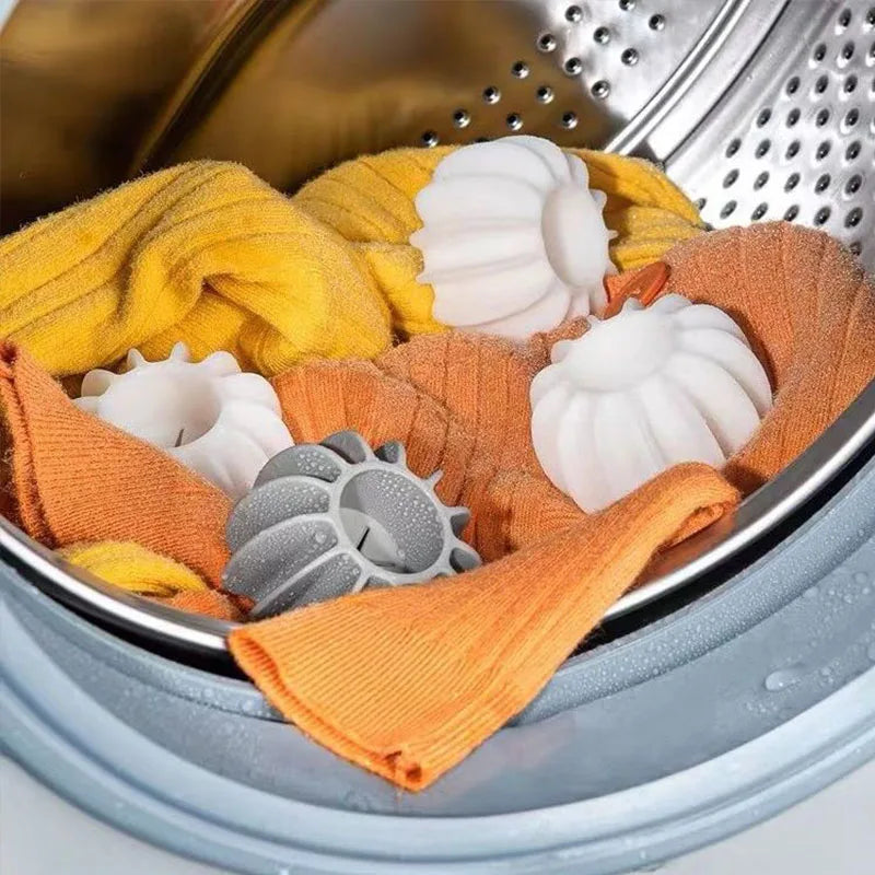 White and grey ribbed silicone laundry balls with yellow and orange fabric inside a washing machine drum.