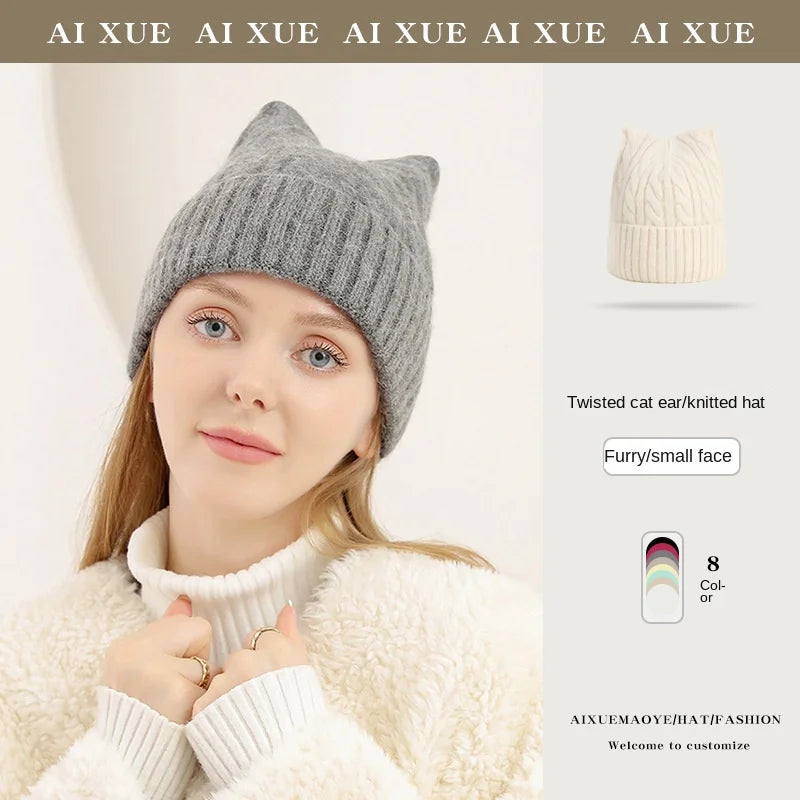 Grey knitted beanie with cute cat ear design, ribbed texture, and soft finish. Worn by a woman in a white jumper.