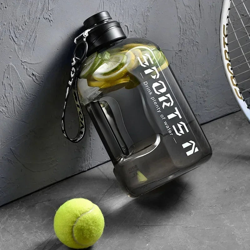 Large grey transparent sports water bottle with black lid and carry strap, featuring lemon slices and tennis gear.