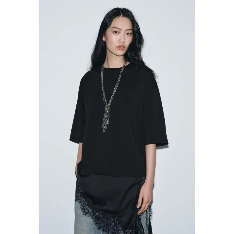 Model wearing a black, oversized t-shirt with a long silver beaded necklace and a black lace-trimmed hem layer.
