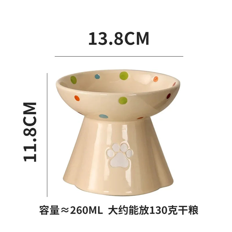 Cream ceramic elevated cat bowl with colourful polka dots and a paw print design, measuring 13.8cm wide by 11.8cm high.