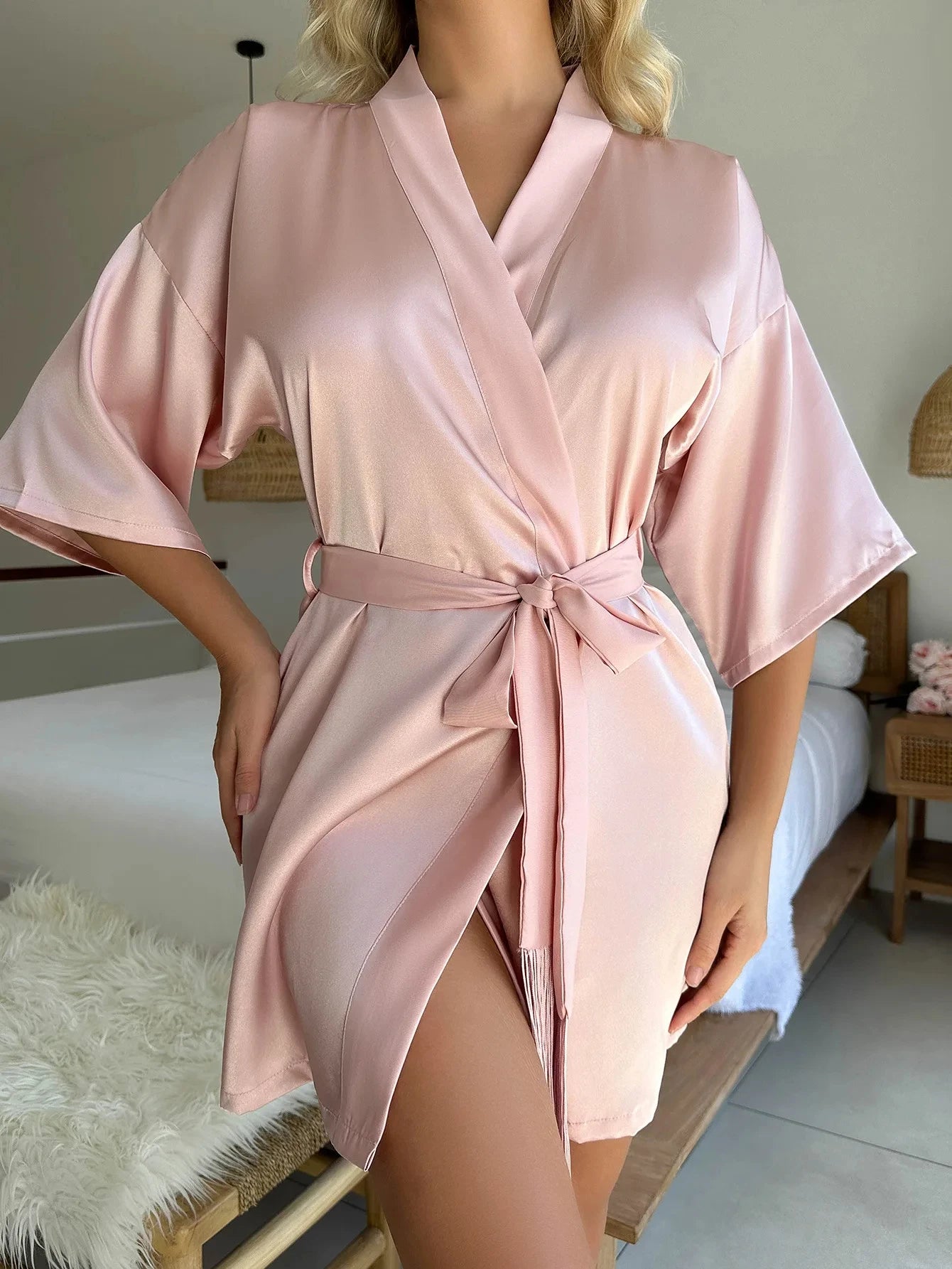 Soft pink satin dressing gown with wide sleeves and a matching tie-waist belt. Short, elegant lounge robe.