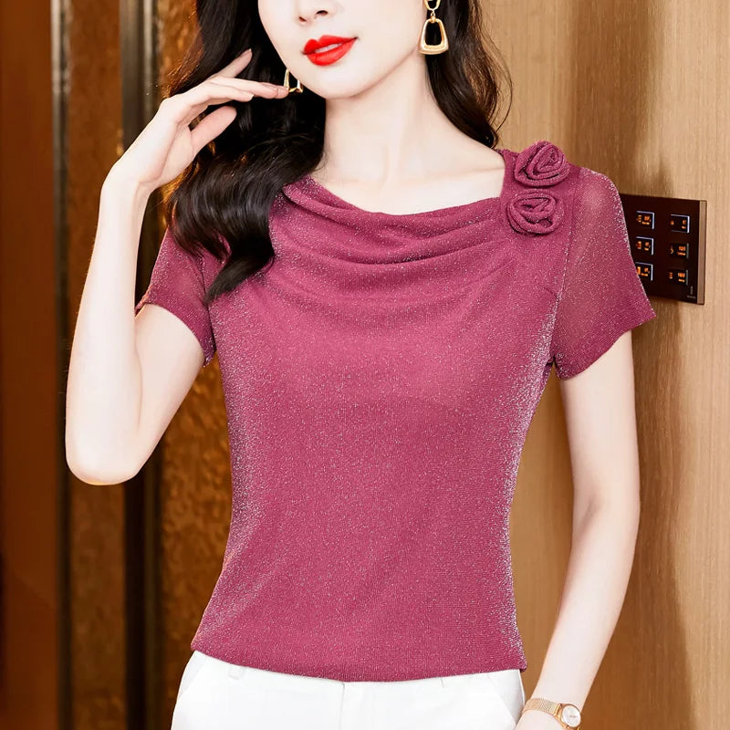 Magenta shimmer short-sleeve top with a cowl neckline and decorative fabric rose detail on the shoulder.