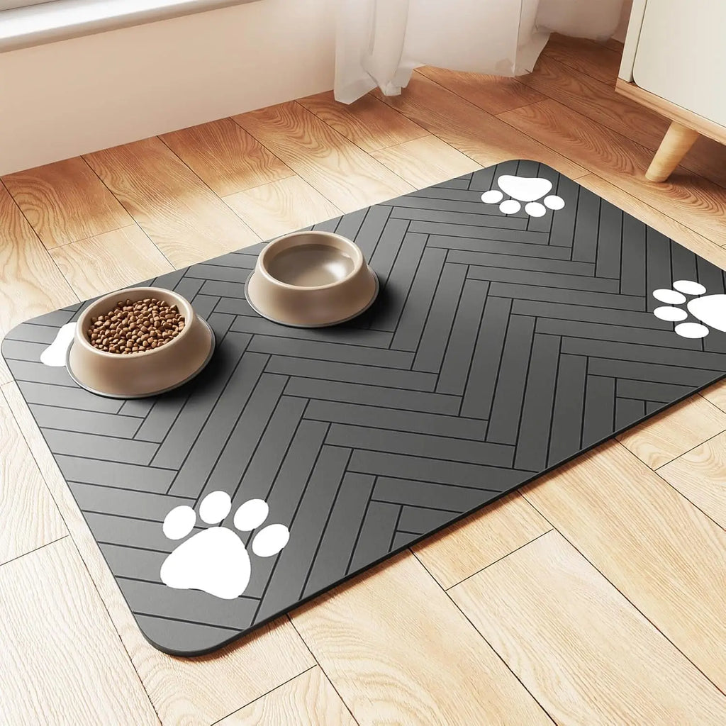 Grey rectangular pet feeding mat with a herringbone pattern and white paw print accents, holding two food bowls.