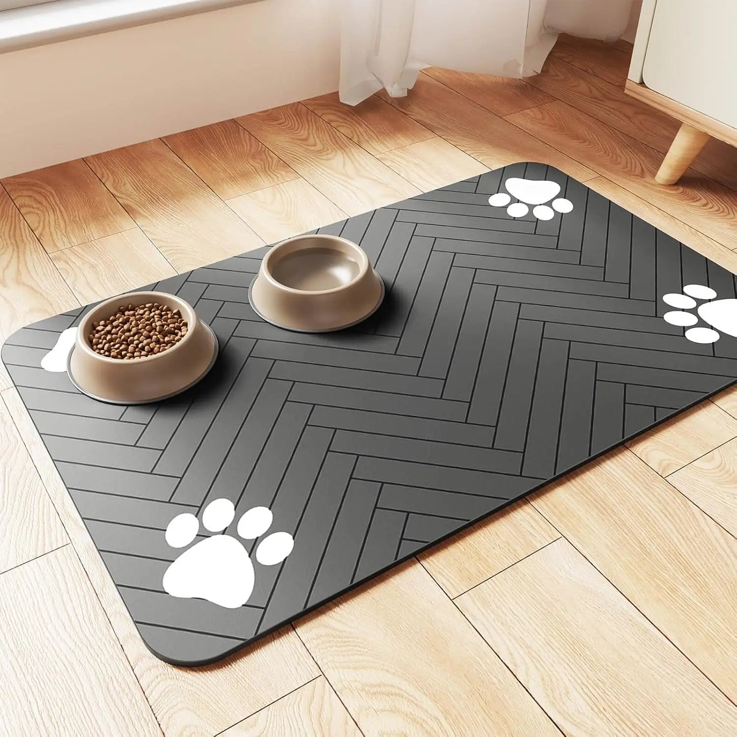 Grey rectangular pet feeding mat with a herringbone pattern and white paw print accents, holding two food bowls.