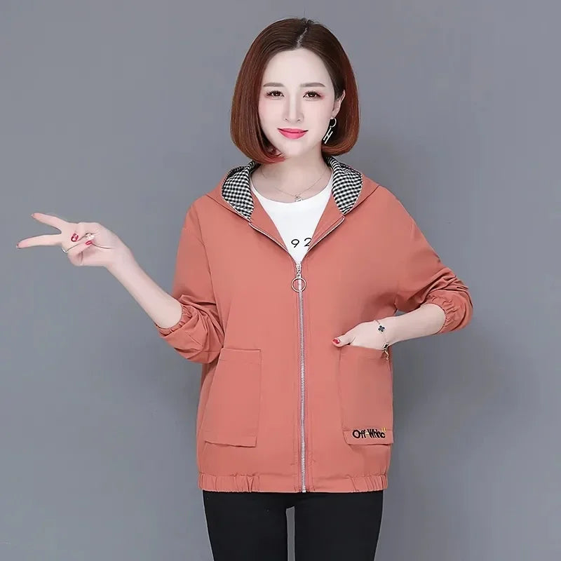 A woman wearing a peach-coloured zip-up hoodie with a black and white gingham lined hood and front patch pockets.