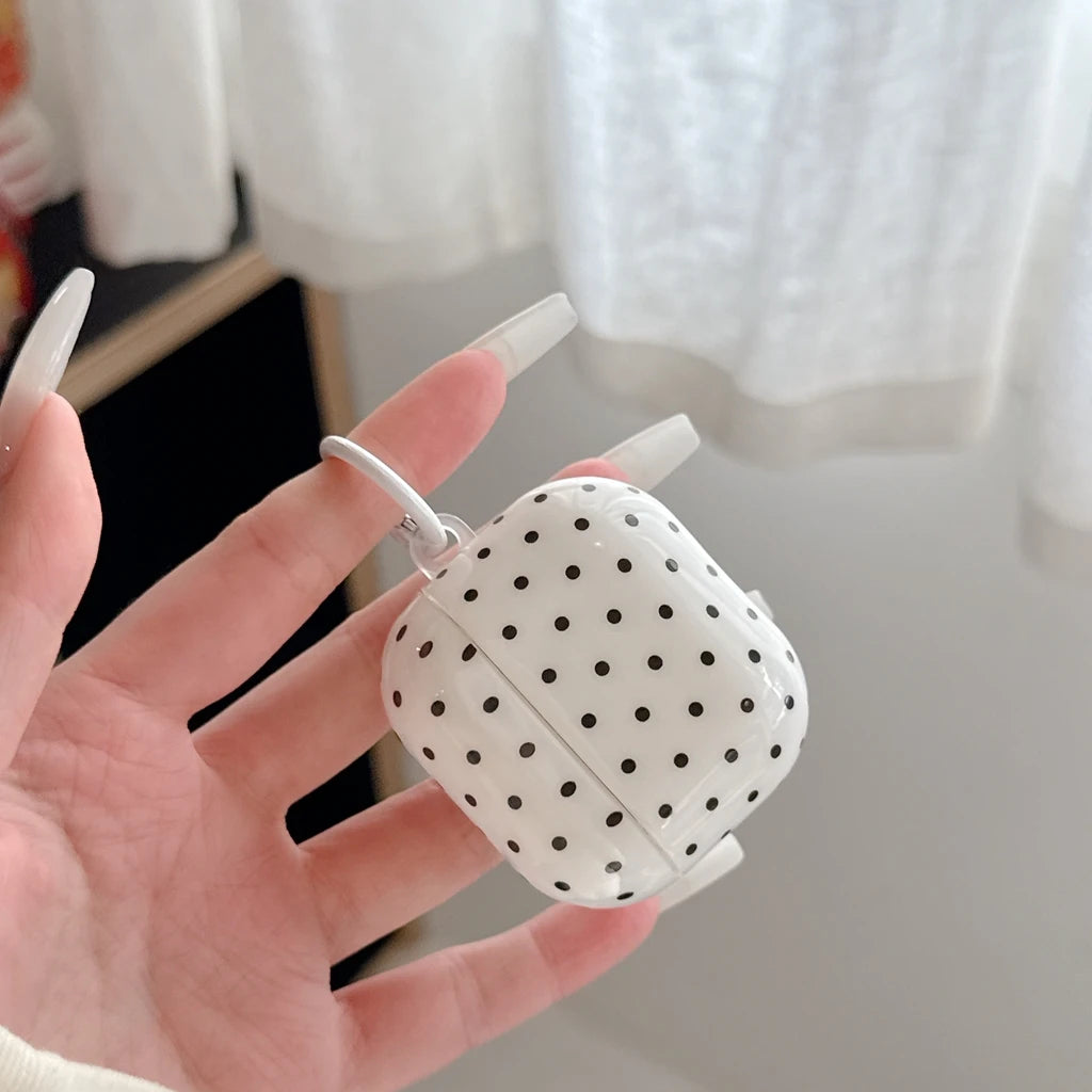 Glossy white AirPods Pro case with black polka dots, featuring a built-in hanging loop.