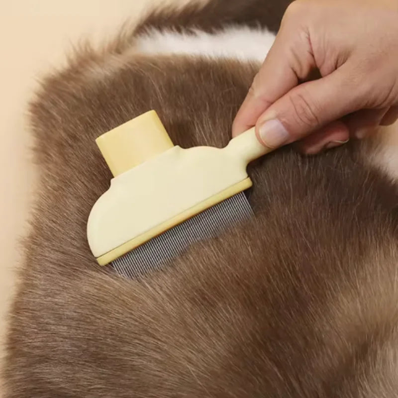 A hand holding a cream-coloured pet grooming comb with fine metal teeth, brushing brown pet fur.