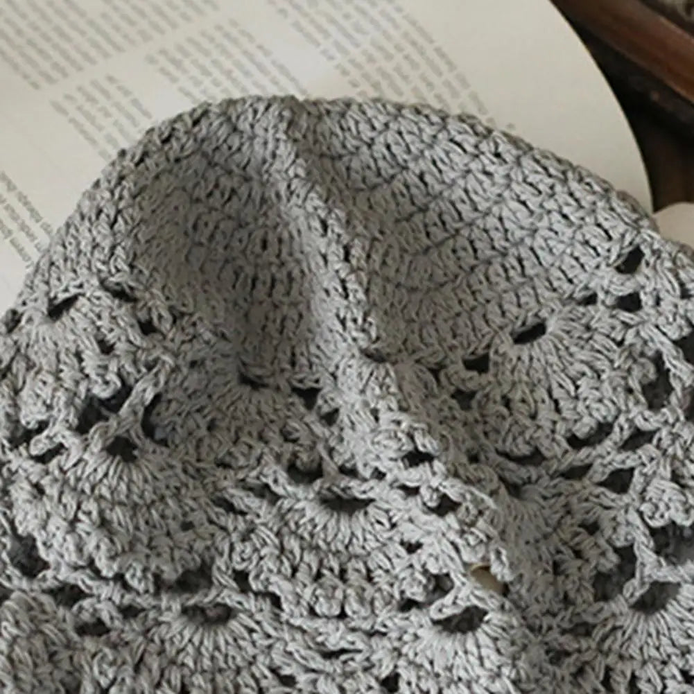 Close-up of a grey women's crochet hat featuring an intricate, hollow lace pattern.