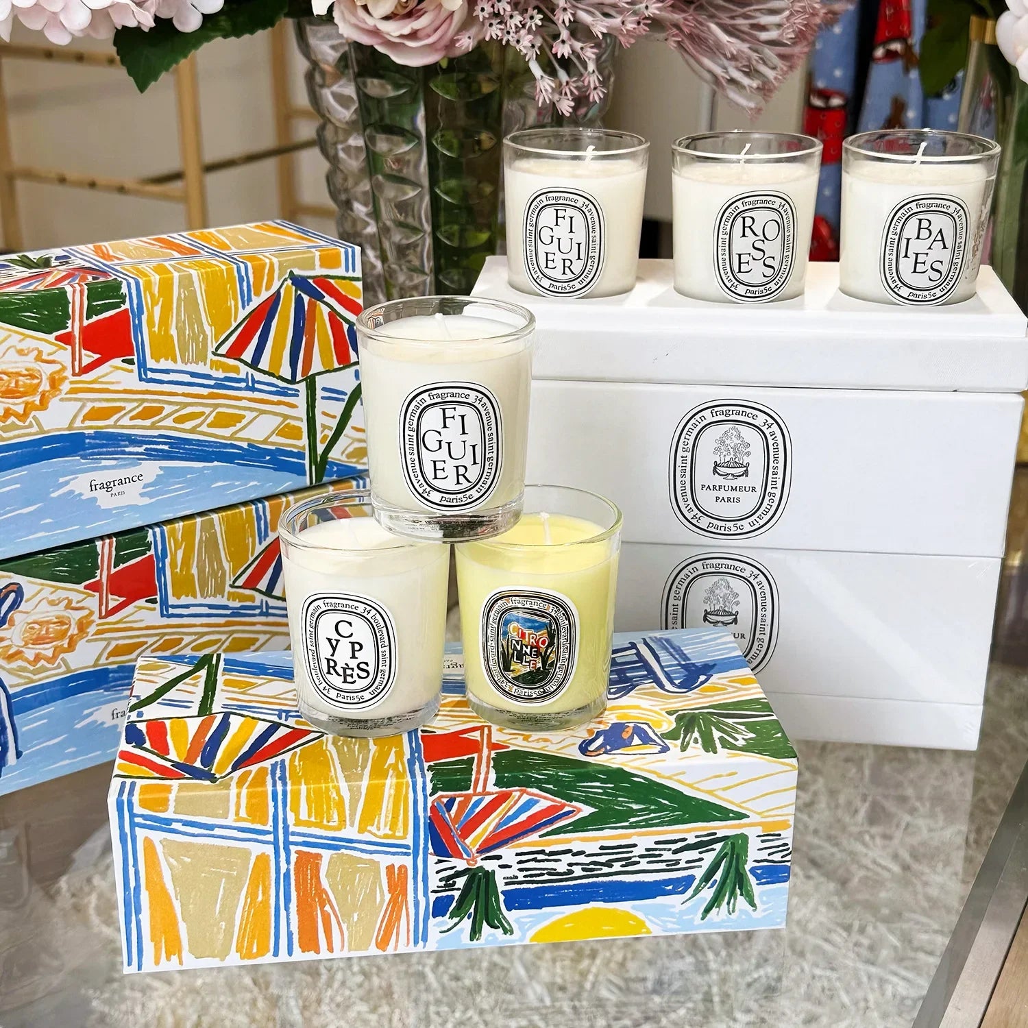 Luxury scented candles in glass jars with oval labels, displayed with colourful, artistic gift boxes.