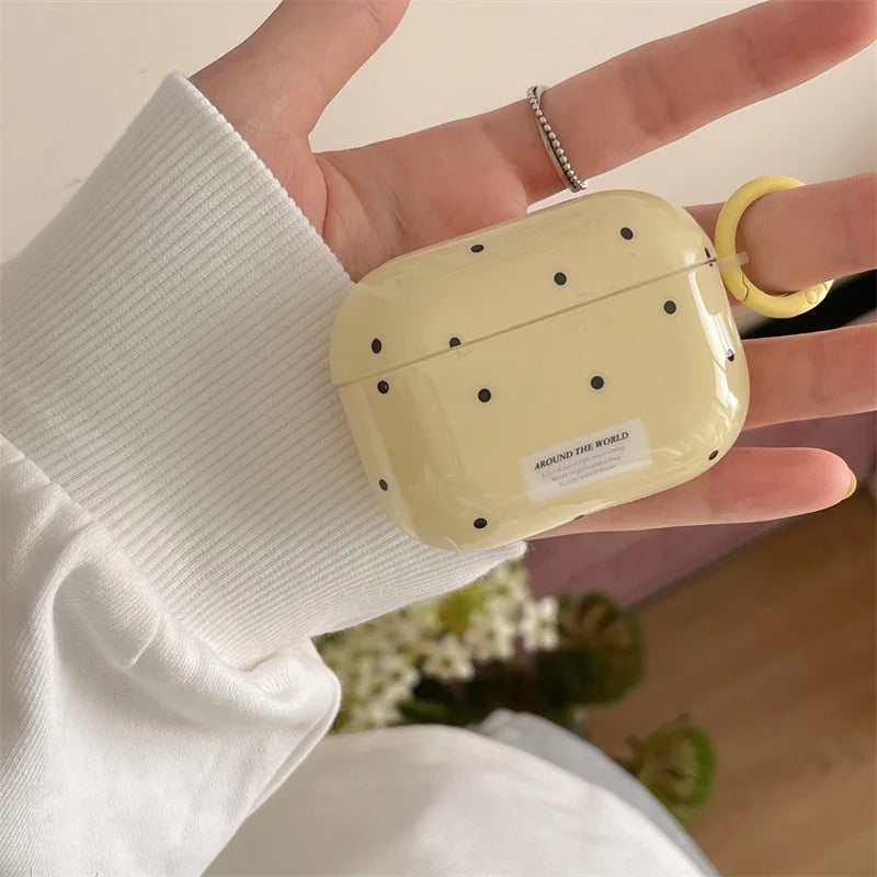 Glossy pale yellow polka dot AirPods Pro case with keyring, held in hand.