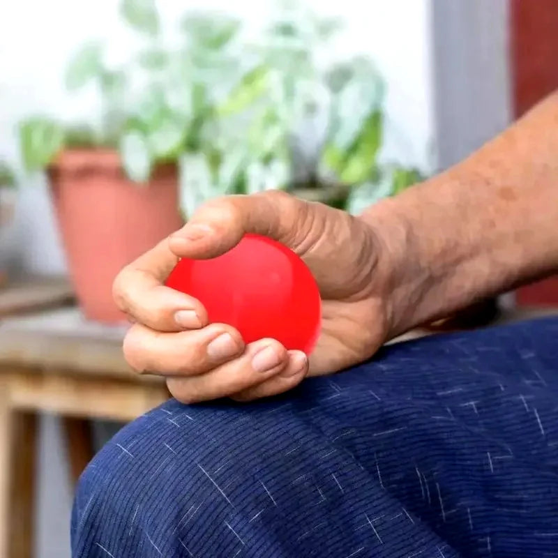 A person holding a small, smooth, bright red stress relief ball in their hand.
