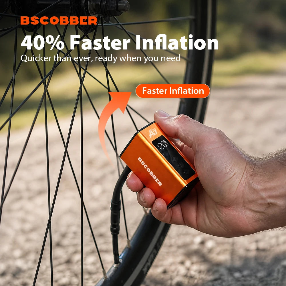 Hand holding a compact, orange BSCOBBER A3Nano mini electric air pump connected to a bicycle tire valve.