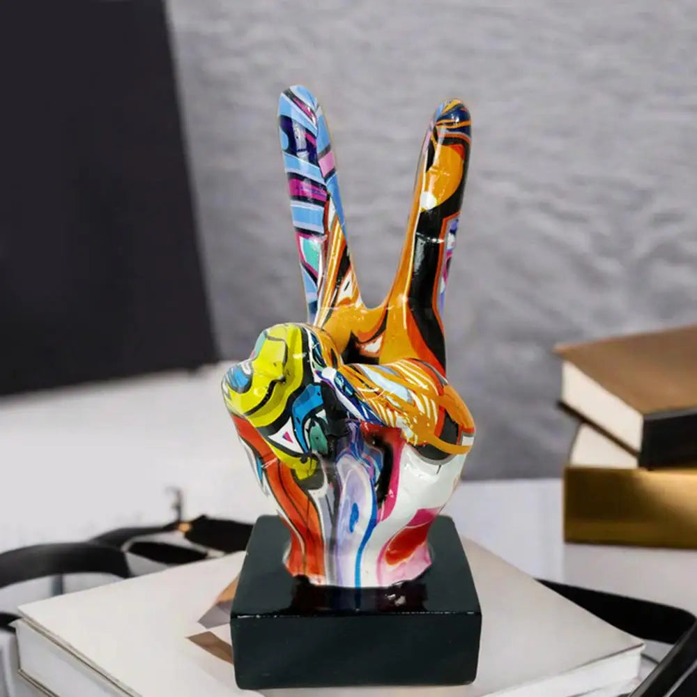 Contemporary table ornament featuring a vibrant, multi-coloured graffiti-style peace sign hand sculpture on a black base.