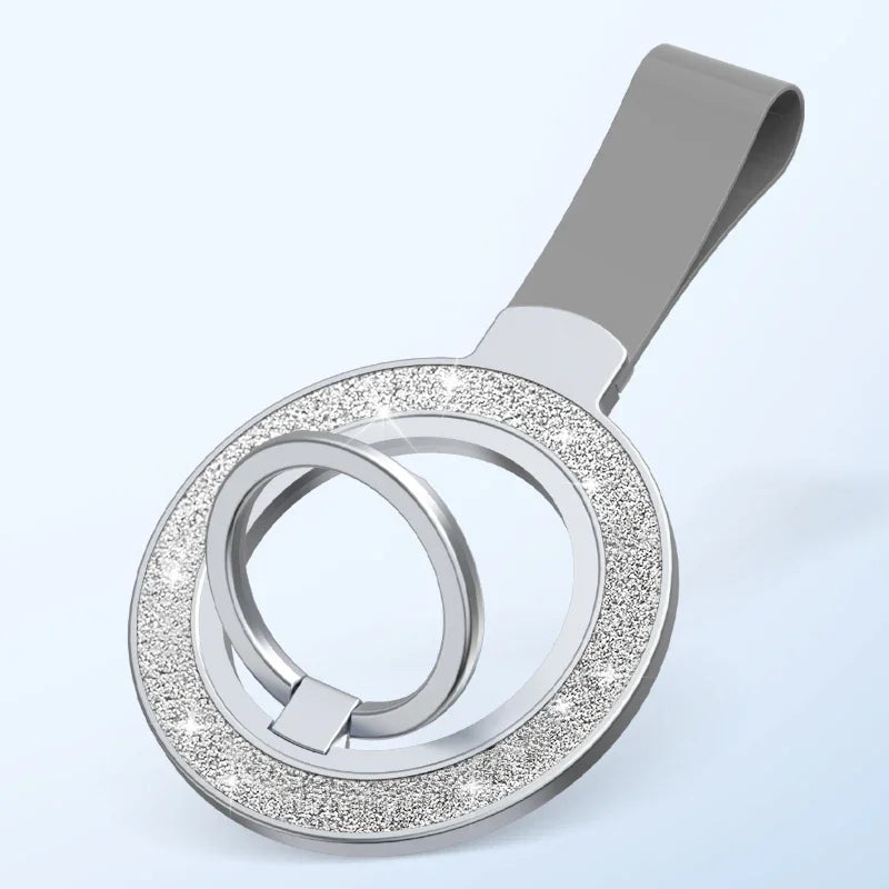 Silver circular phone ring holder with a glittery crystal-style finish and grey strap on a light blue background.