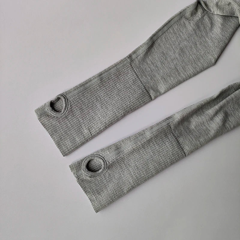 Grey long-sleeved athletic top sleeves with thumbholes, featuring a textured, ribbed fabric design.