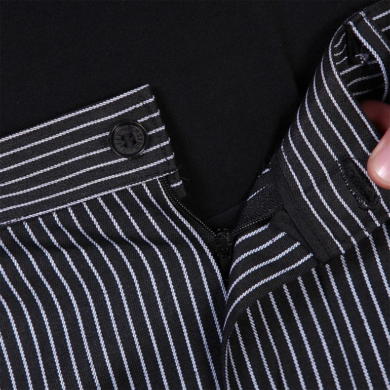 Close-up of black chef trousers with a white pinstripe pattern, featuring a button and zip fly fastening.