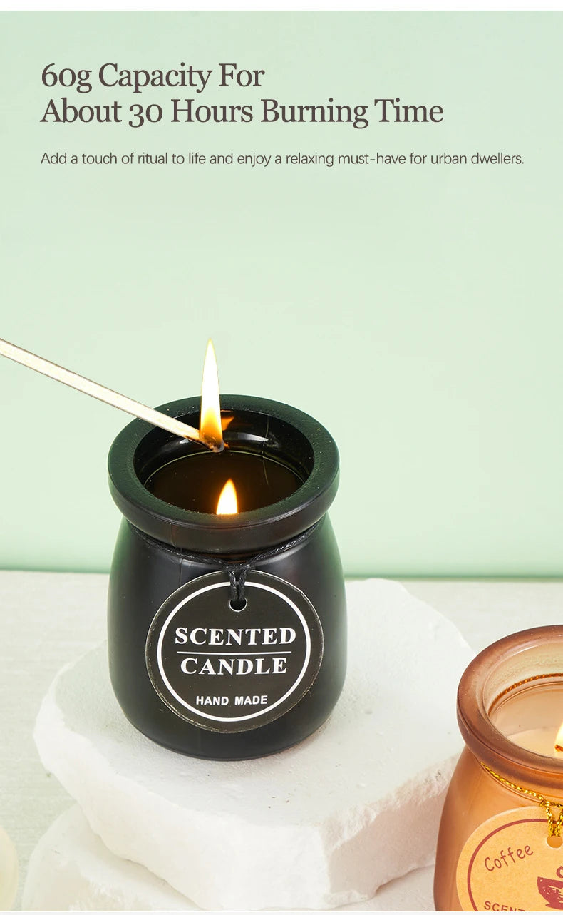 Lit 60g handmade scented candle in a sleek black glass jar with a round label, displayed on a stone base.