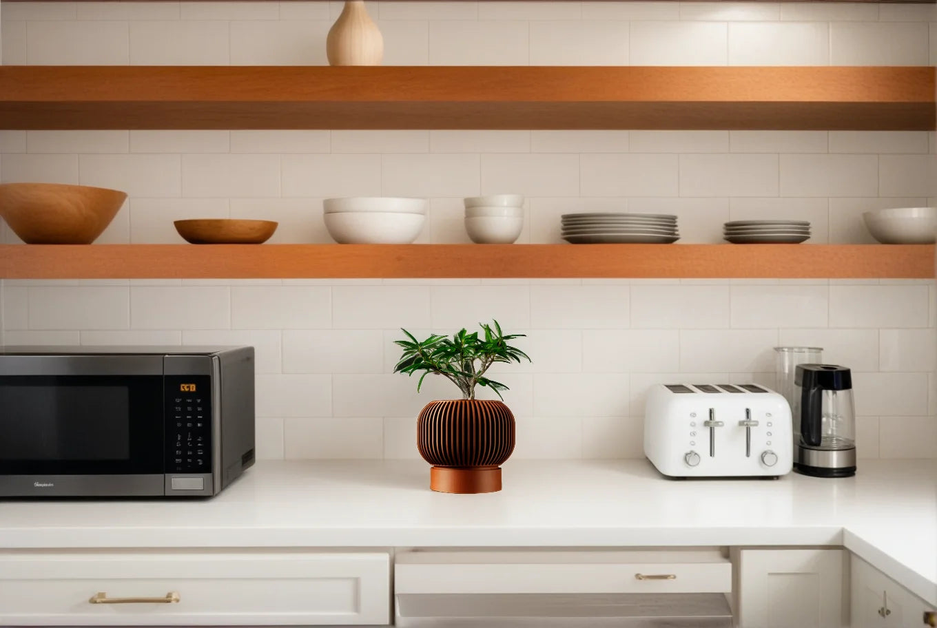 A brown, 3D-printed ribbed plant pot holding a small green shrub on a modern kitchen counter.