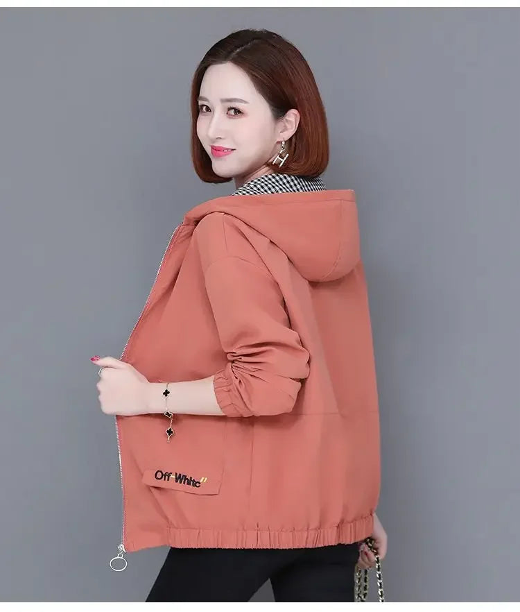 Woman wearing a coral-pink hooded zip-up jacket with long sleeves, elasticated hem, and a small front pocket.