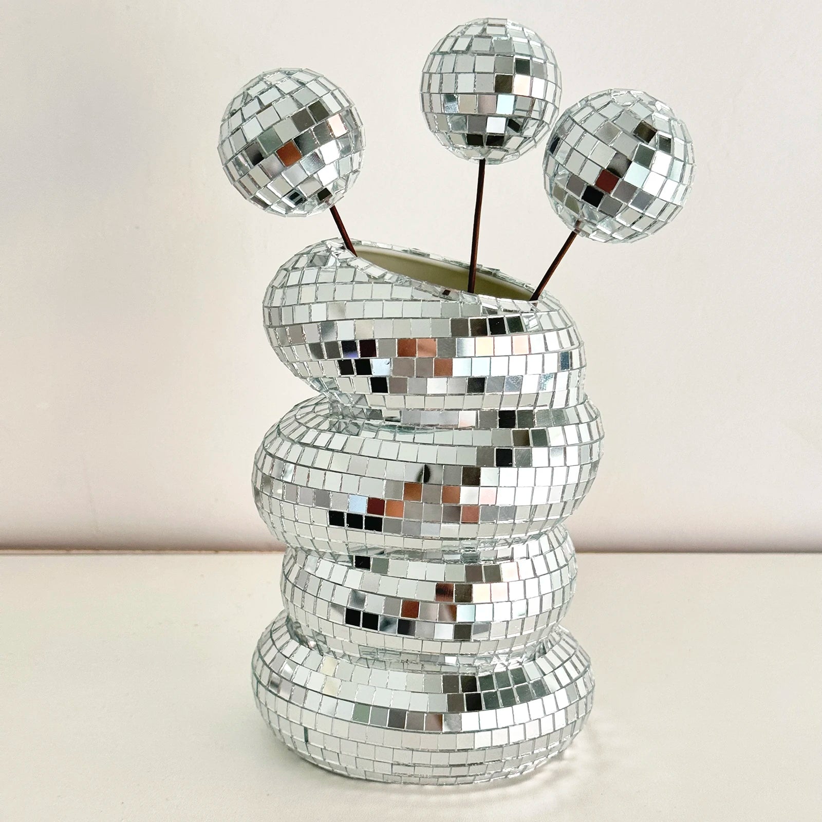 A silver, tiered disco ball vase featuring reflective mosaic tiles, styled with three mini disco ball stems.