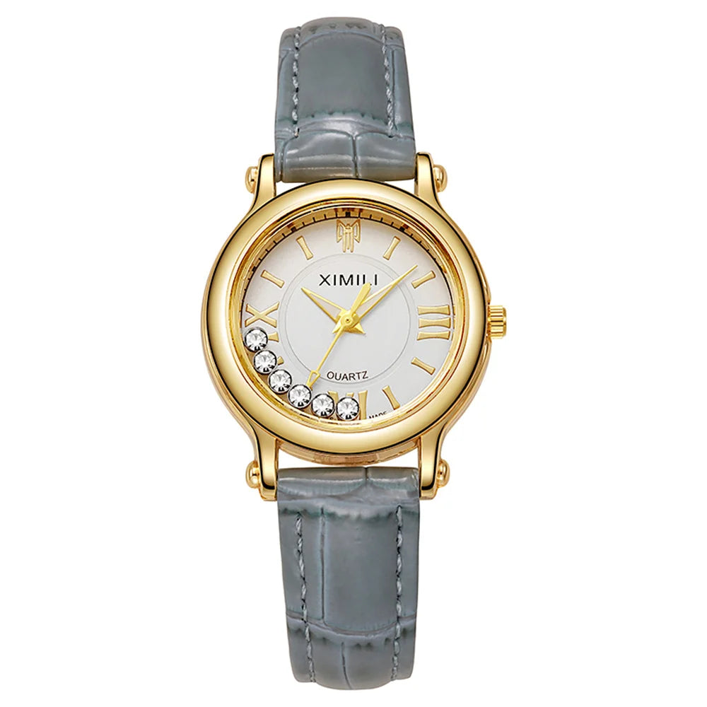 Women's gold-tone quartz watch with a white dial, crystal accents, and a grey textured leather strap.