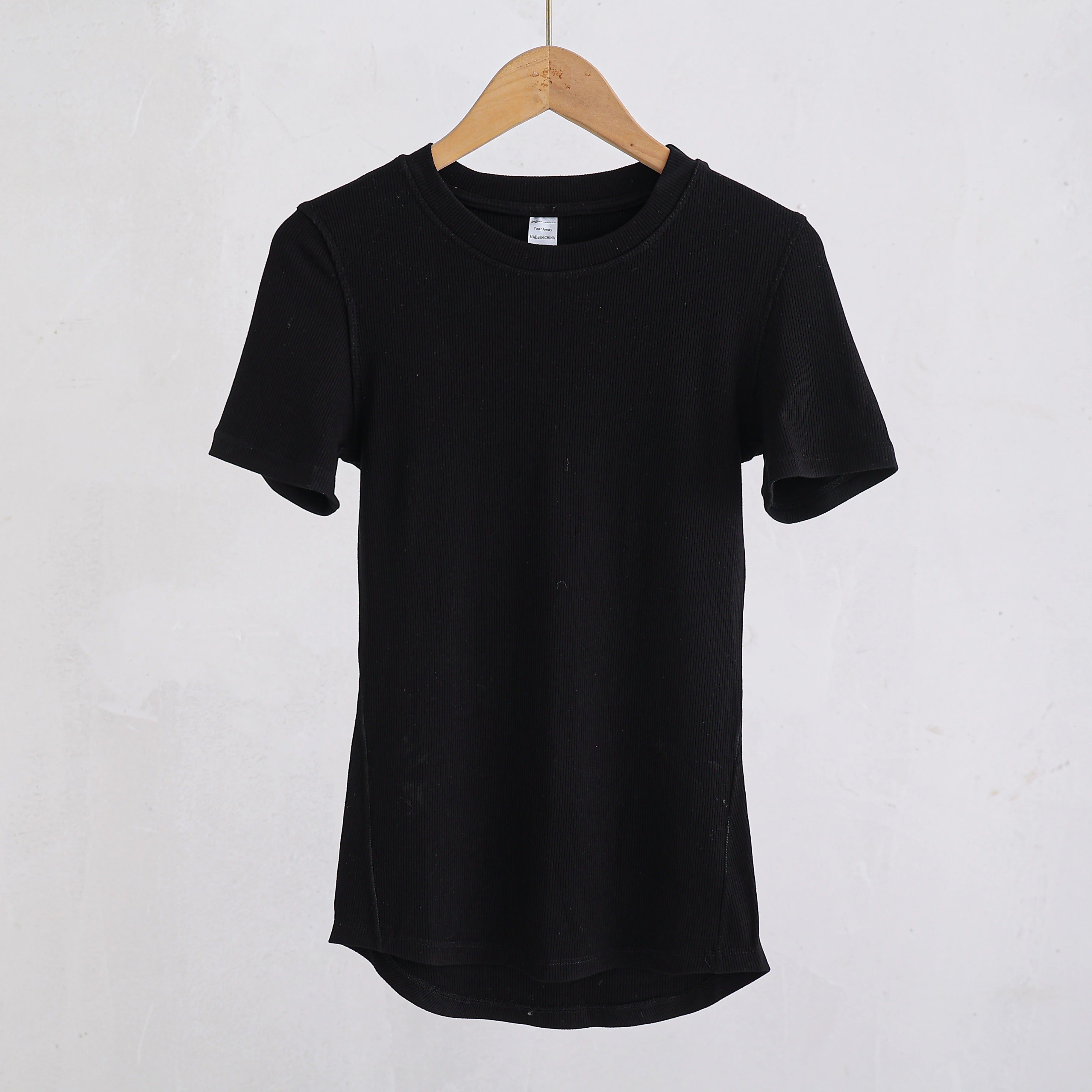 Black short-sleeved t-shirt in a ribbed knit fabric with a classic crew neck, hanging on a wooden hanger.