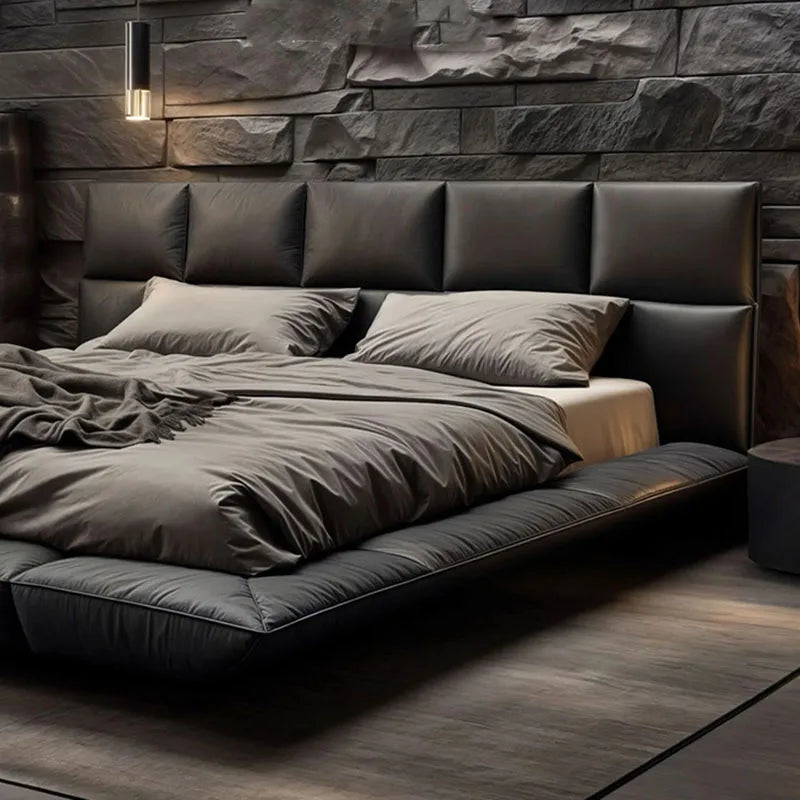 A modern, low-profile black leather king-size floating bed with a wide, panelled headboard.