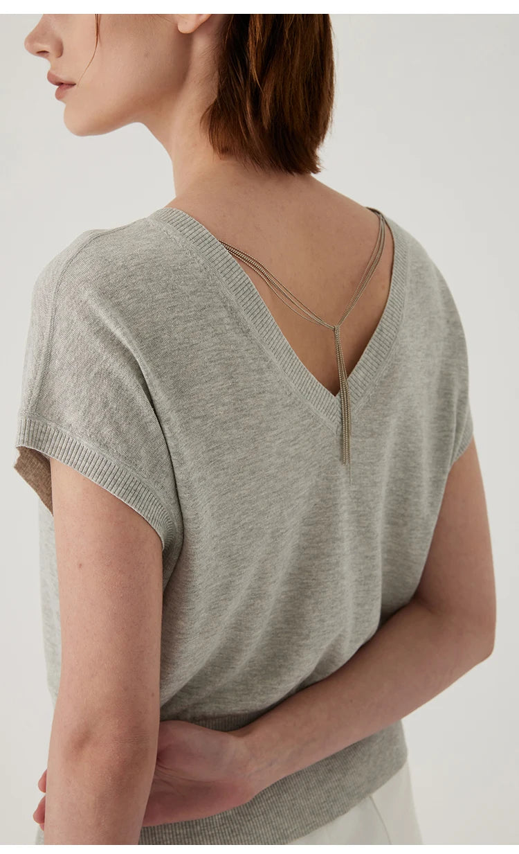 Grey knitted V-neck top with short sleeves and delicate hanging gold-tone chain detail at the back.