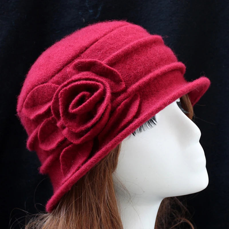 Elegant red wool winter hat featuring a decorative felt flower and subtle pleated brim on a mannequin head.