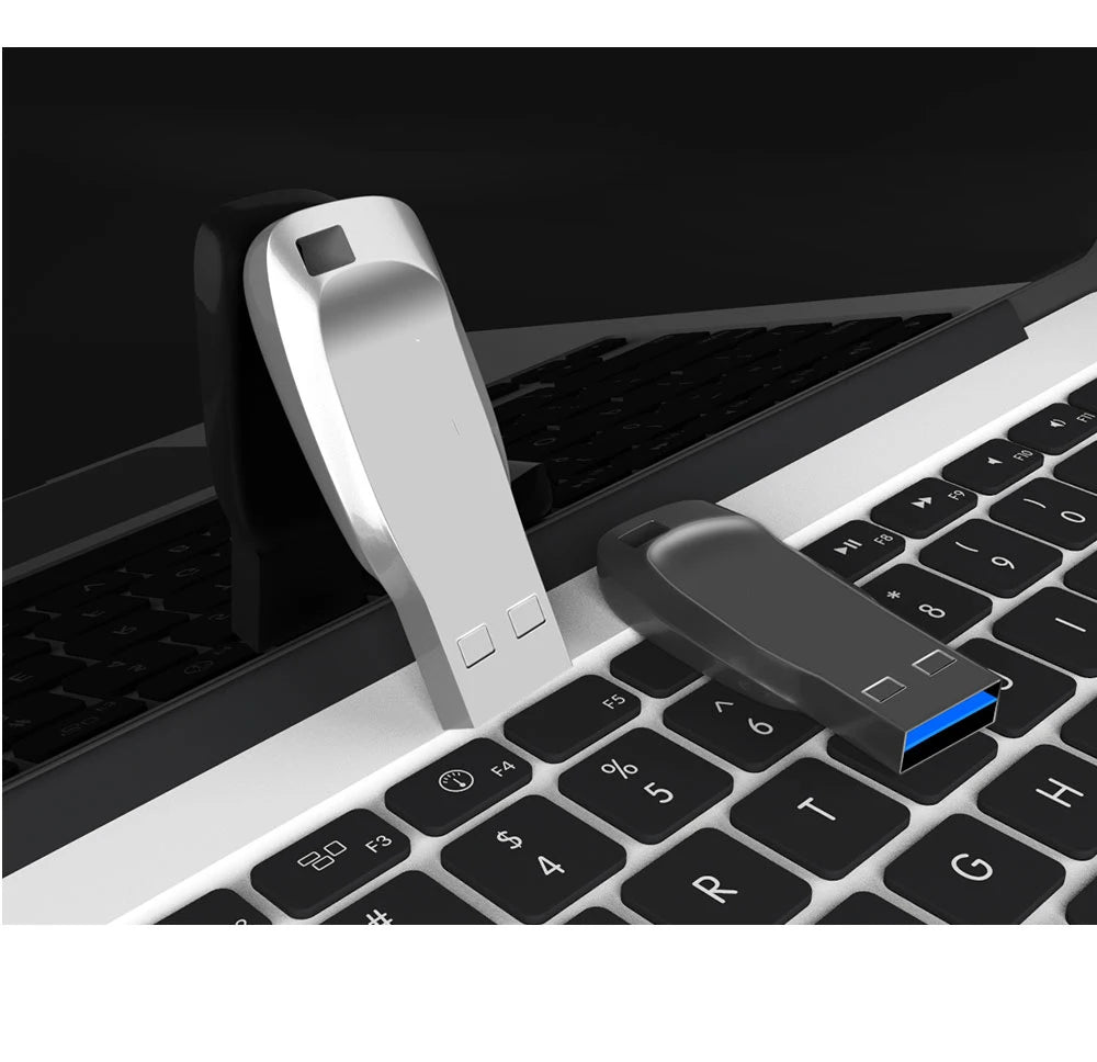 Silver and black metal USB 3.0 flash drives resting on a laptop keyboard.