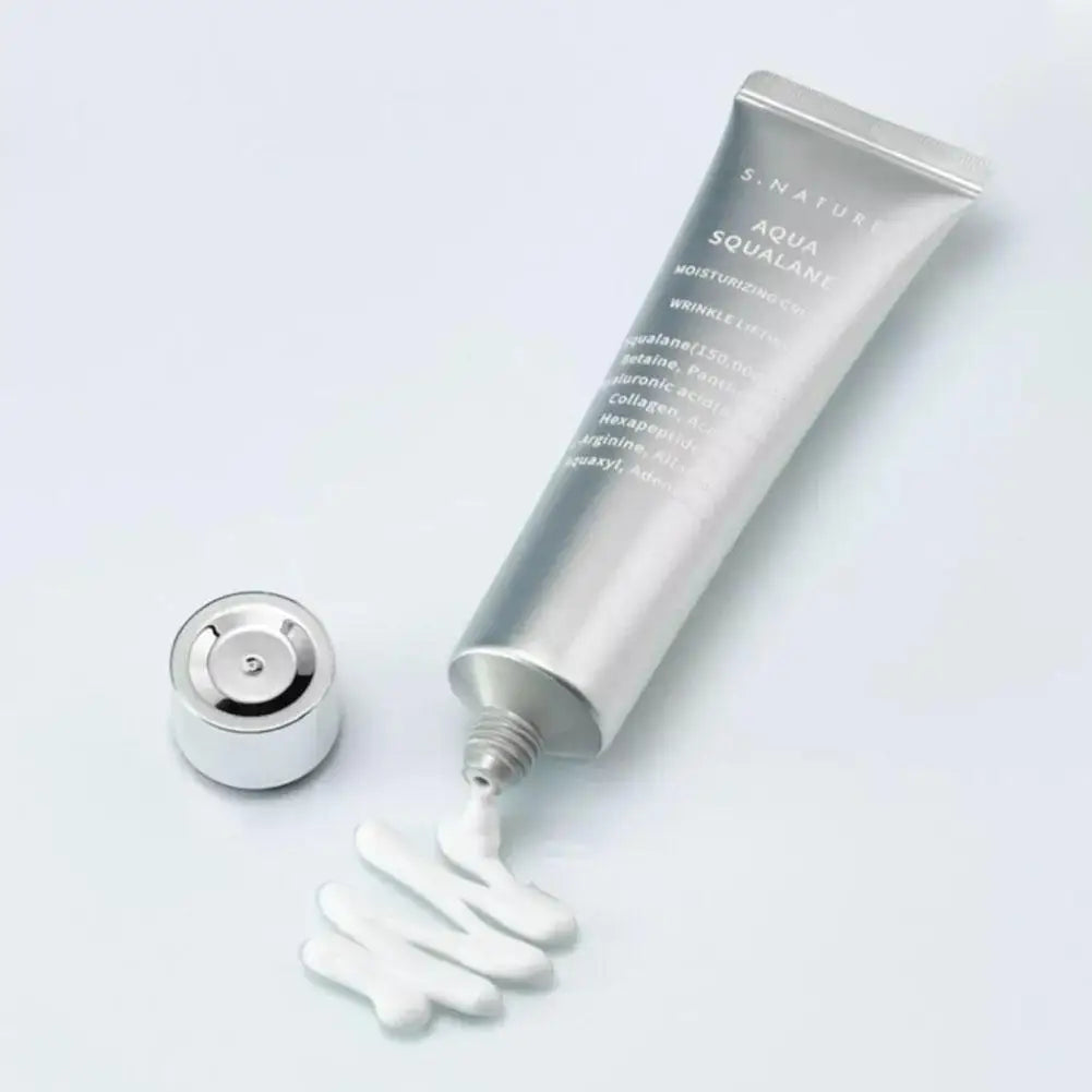 Silver tube of moisturising cream with cap removed, showing a white, creamy texture being squeezed out onto a surface.