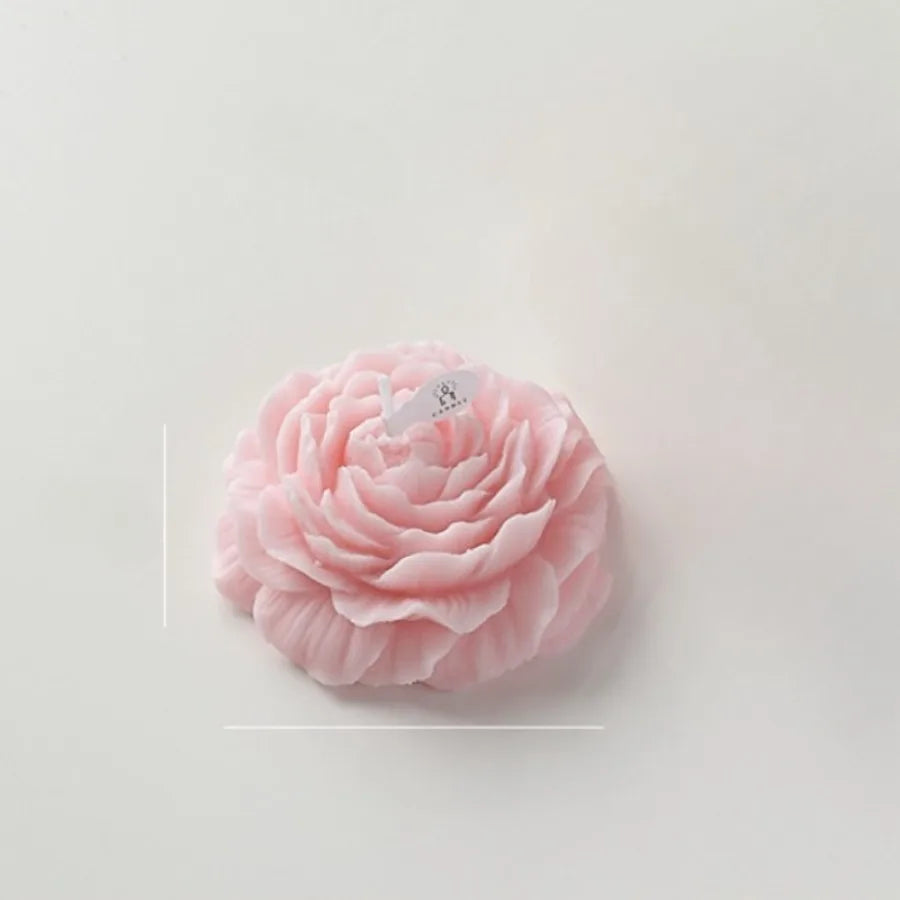 Pale pink flower-shaped candle with detailed layered petals, set against a clean white background.