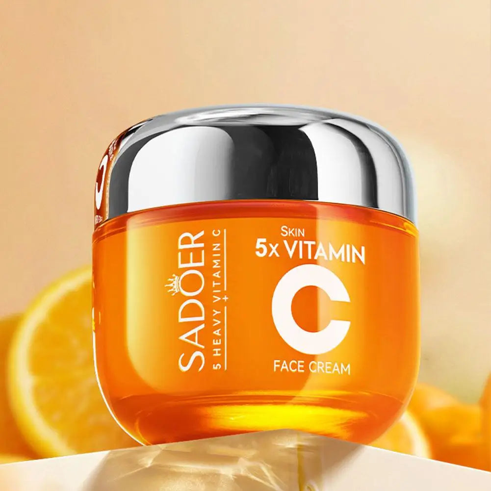 Orange glass jar of 5x Vitamin C face cream with a shiny silver lid against a citrus-themed background.