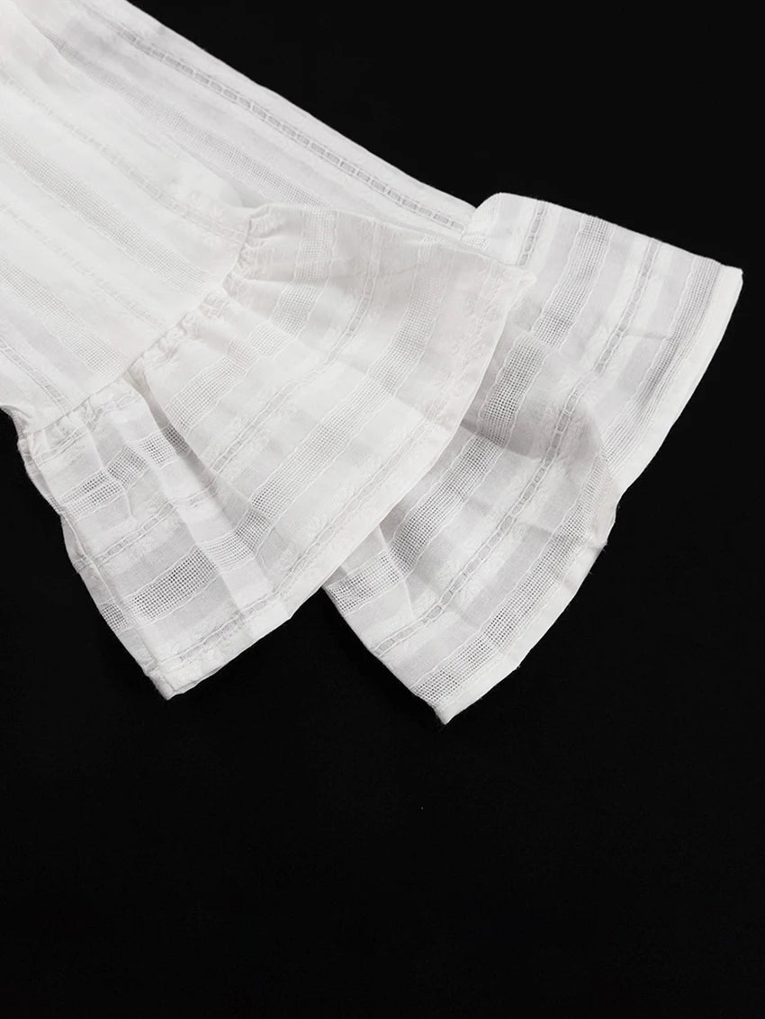 White long-sleeve top with sheer striped texture and layered ruffled cuffs on a black background.