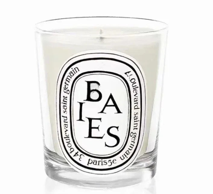 White scented candle in a clear glass votive with a decorative black and white oval label.