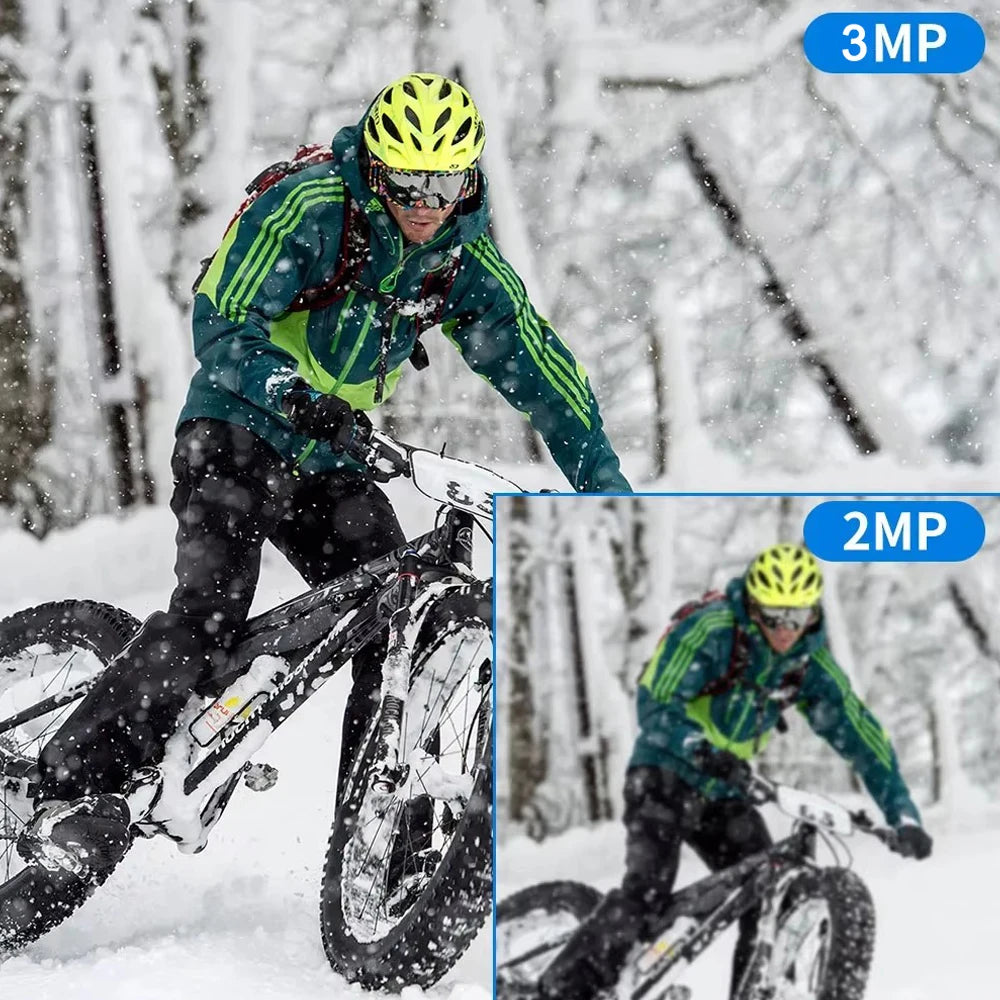 A cyclist in a green jacket and yellow helmet rides a black mountain bike through snow, showing 3MP and 2MP resolution.