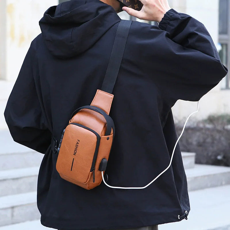 Tan faux leather anti-theft crossbody sling bag with a built-in USB charging port, worn by a man in a black jacket.