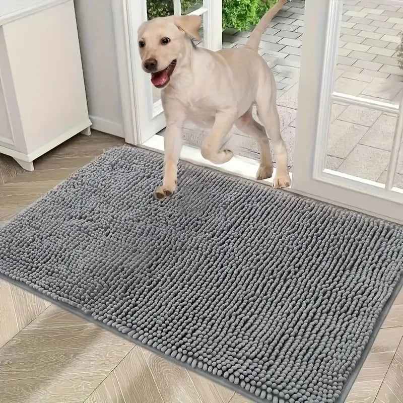 A happy puppy stepping onto a rectangular, grey, highly absorbent microfibre doormat with a soft, textured finish.