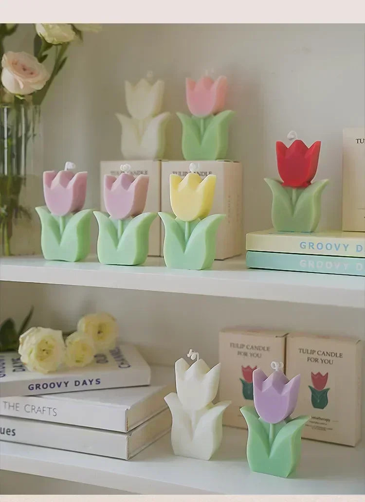 A collection of colourful, tulip-shaped candles in pastel and bright shades, each set on a light green leaf base.