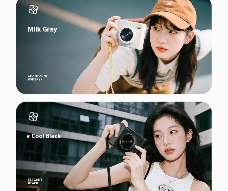 Two women holding compact digital cameras, one in matte milk gray and one in matte black, with wrist straps attached.