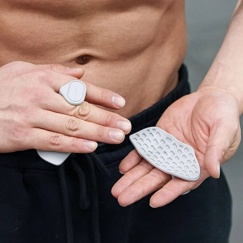 A person wearing light grey, textured silicone palm pads with ring loops for grip and hand exercise.