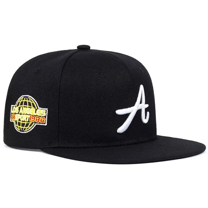 Black hip-hop baseball cap with white 'A' embroidery on the front and a globe patch on the side.