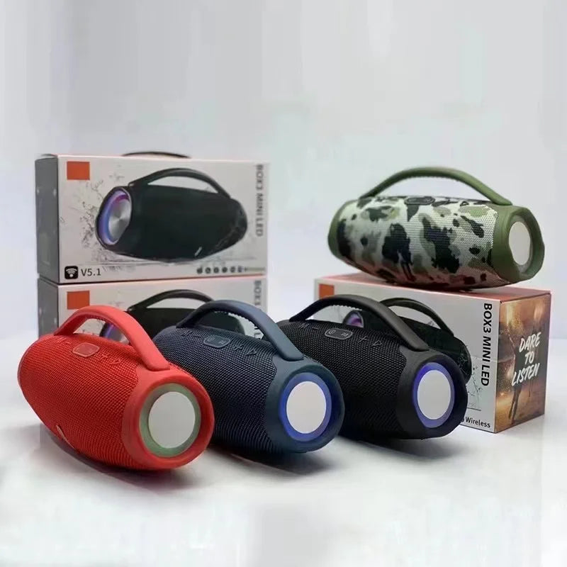 Four portable, cylindrical Bluetooth speakers in red, blue, black, and camouflage with top handles and RGB LED lights.