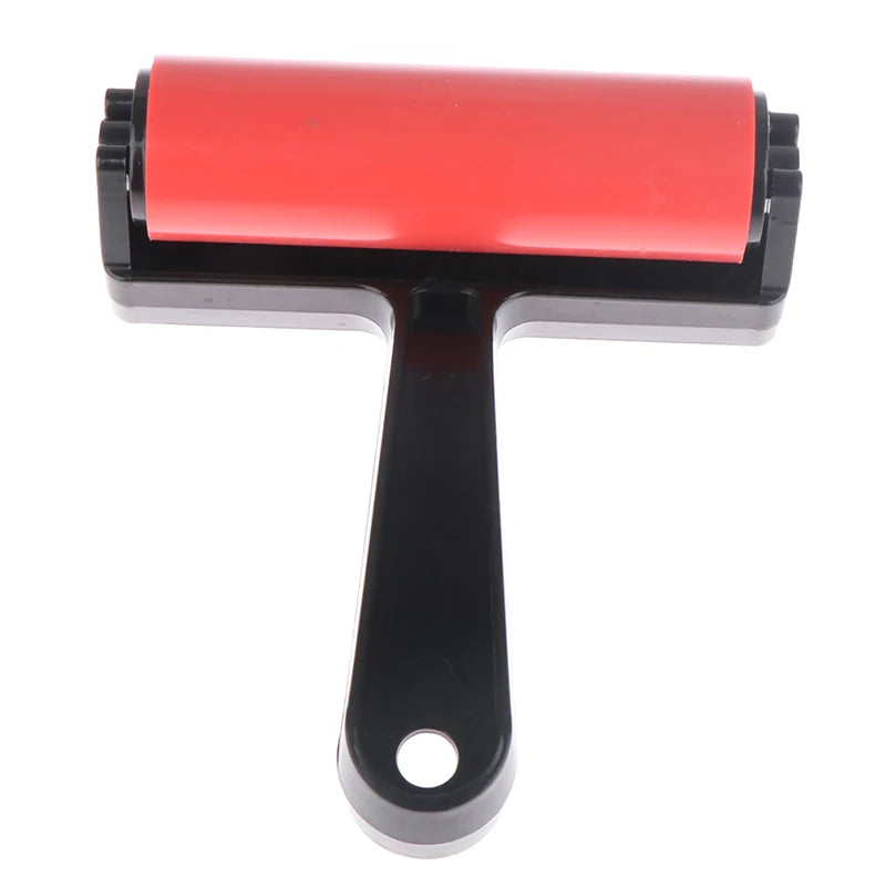 Red rubber brayer roller with a black plastic handle and hanging hole, ideal for crafts and printmaking.