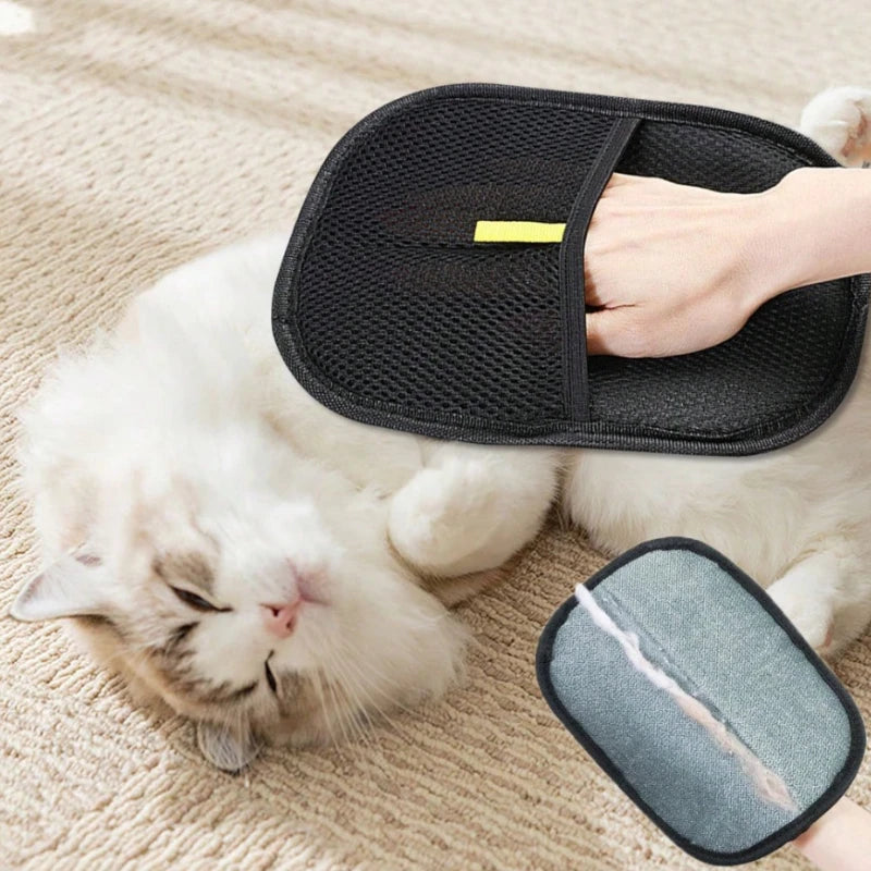 A black mesh pet grooming mitt being used to brush a white long-haired cat lying on a carpet.