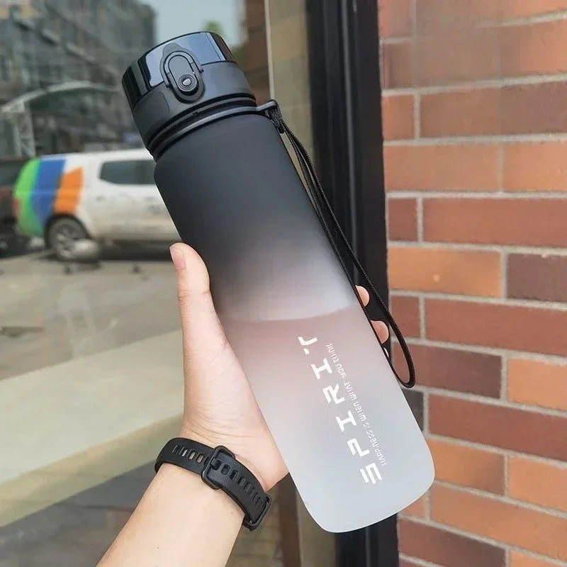 Handheld black-to-clear gradient sports water bottle with a flip-top lid, carry strap, and 'SPIRIT' text.